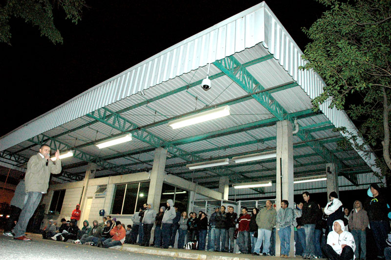 Trabalhadores do primeiro turno, na portaria do grupo, acompanham assembleia conduzida por Valdeci Henrique da Silva